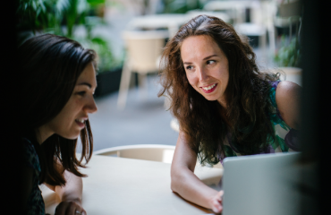 Two women looking at a laptop smiling