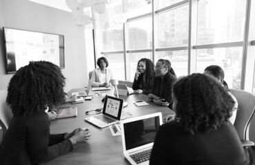 Group of people working on laptops around a table