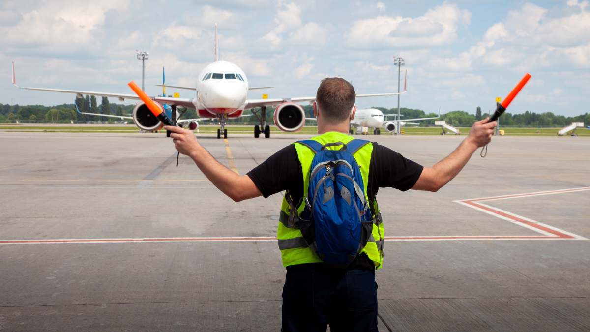 Man in a high vis waving in a plane to park