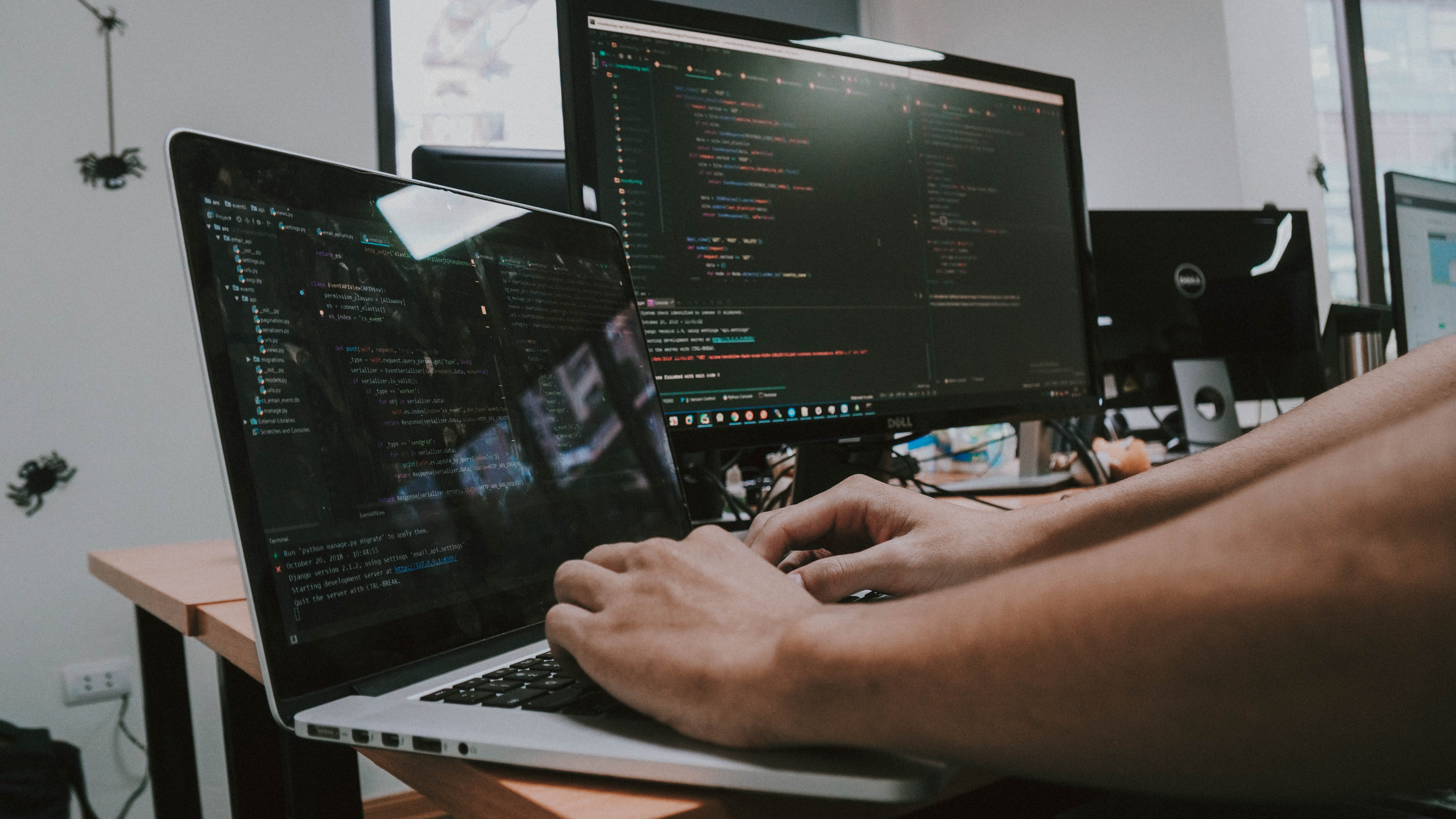 Someone coding on a laptop and monitor