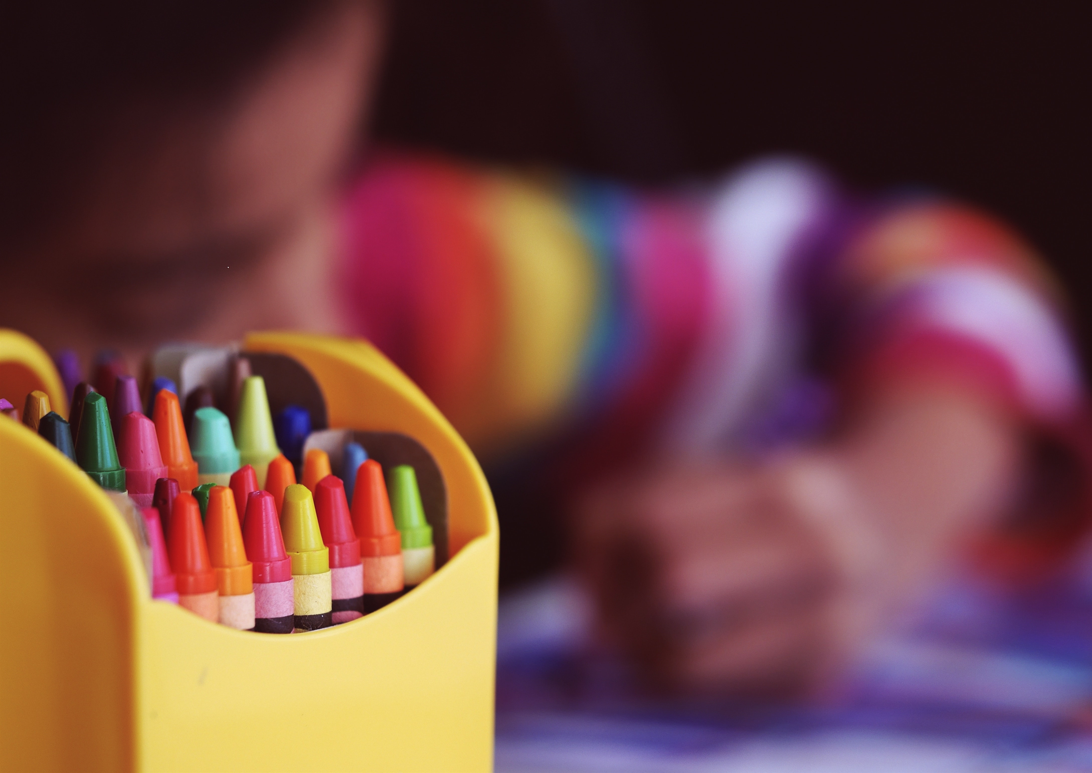 crayons with a child colouring in the background