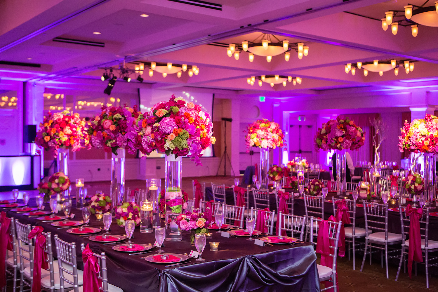 event room with pink lighting and colourful flowers on the dressed tables