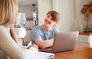 Young man with a women smiling while using a laptop