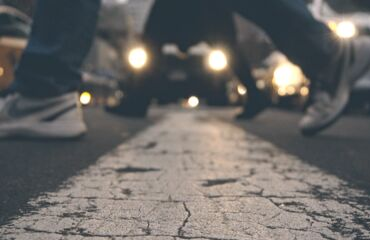 peoples feet crossing a zebra crossing at night