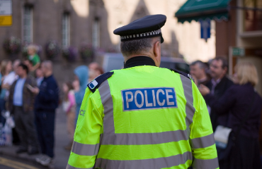 Male police officer walking through a crowd of people