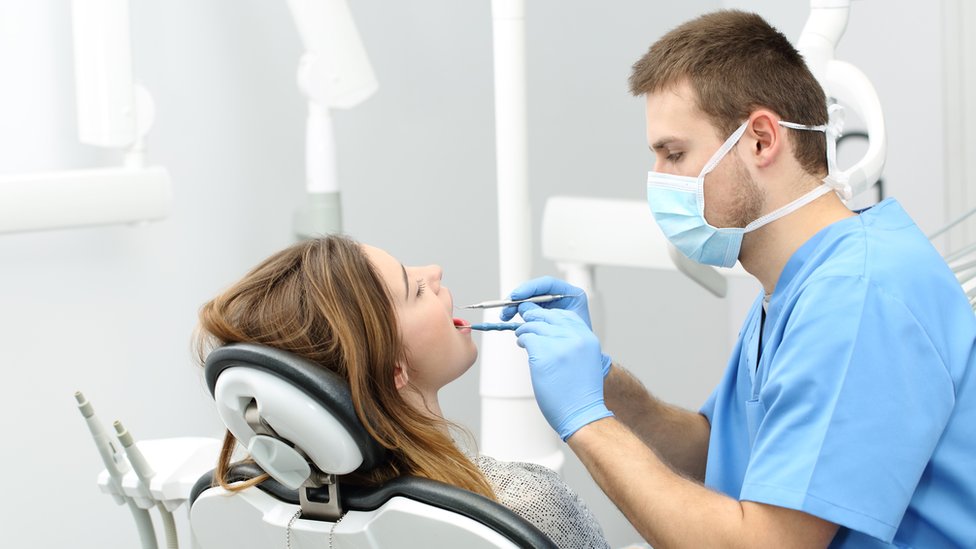 Male dentist looking into a girls mouth