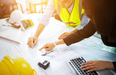 Two people in construction working on plans