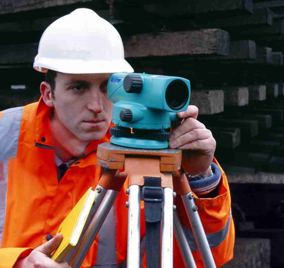 Construction man looking through measuring machinery