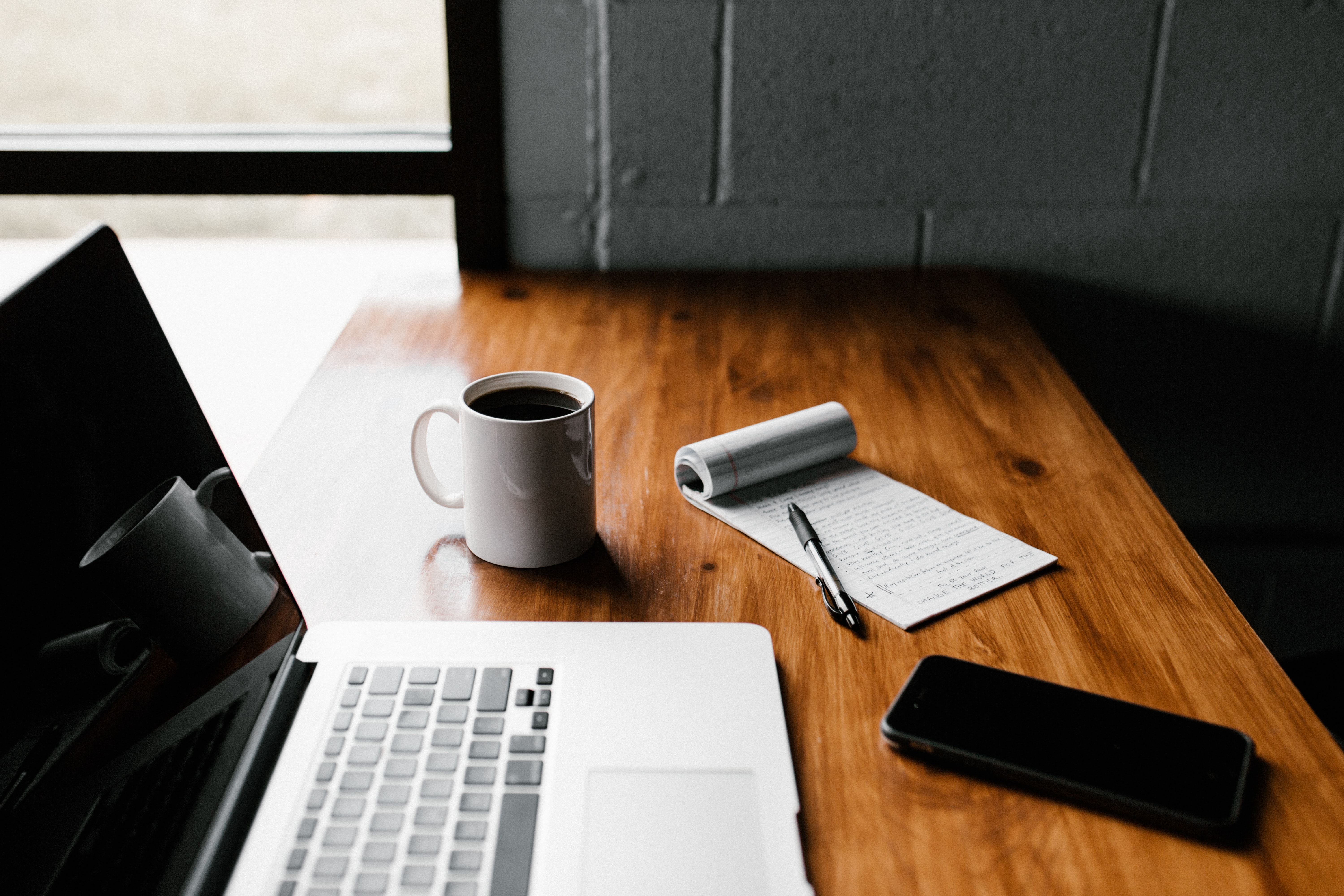 Desk with a laptop on and a notepad and coffee