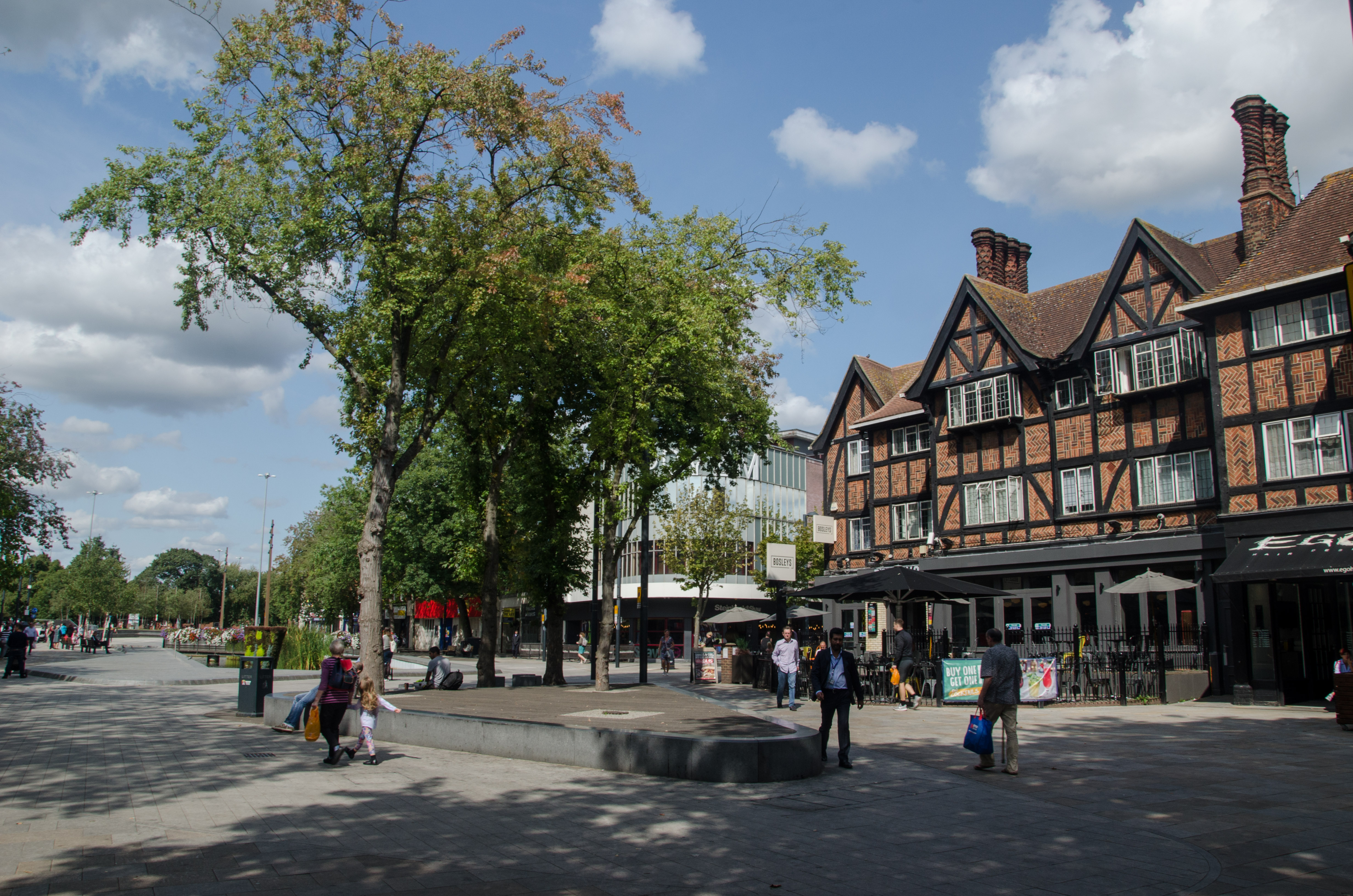 Highstreet in Watford showing historical buildings, trees and people walking in the street 