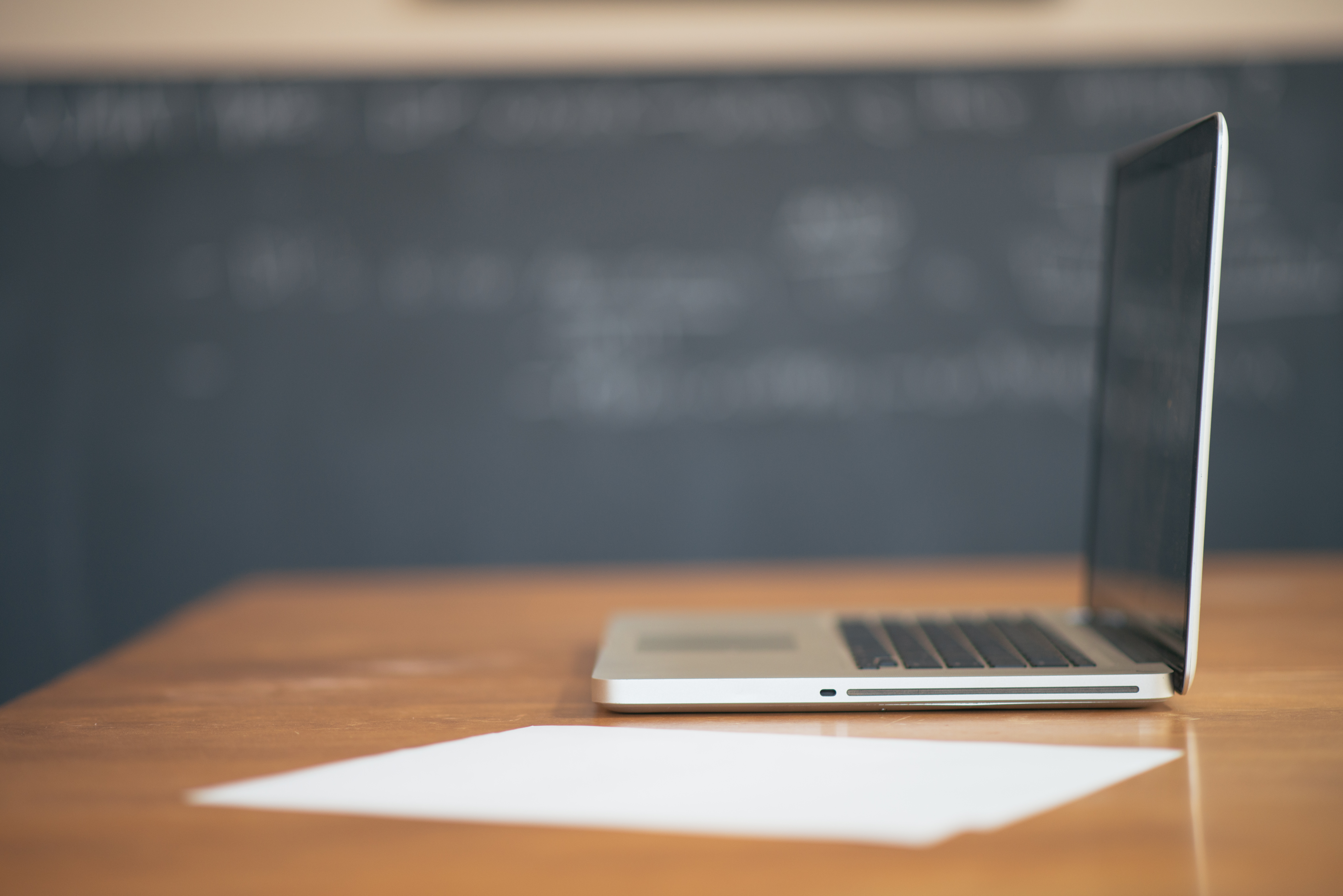 Laptop on a table with a chalk board in the background