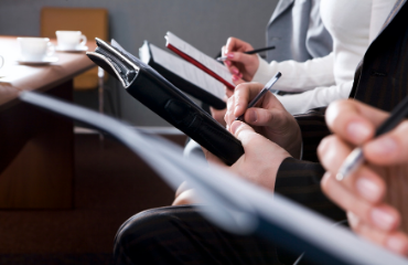 People sat down taking notes in a professional environment 