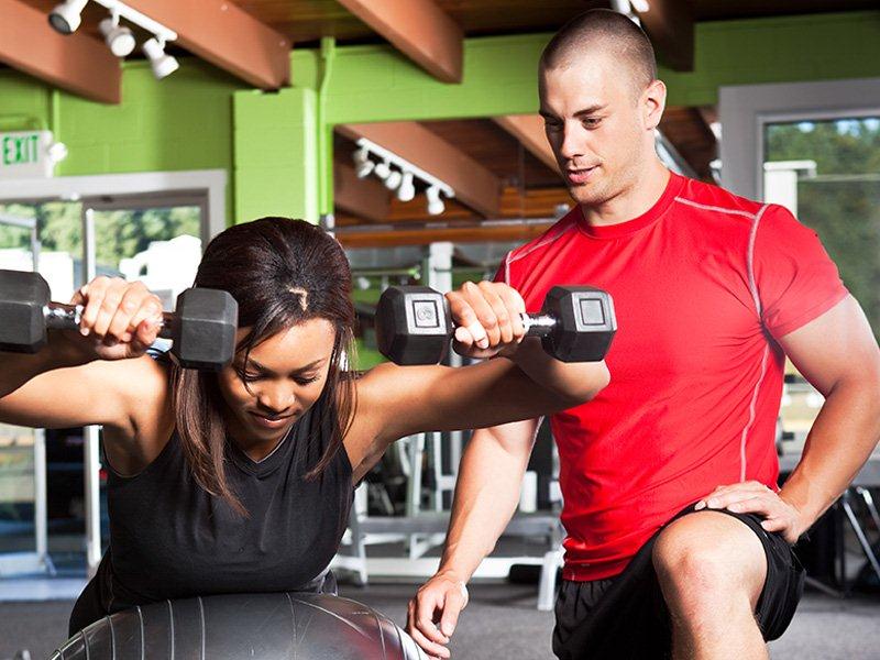 Male personal trainer helping a female