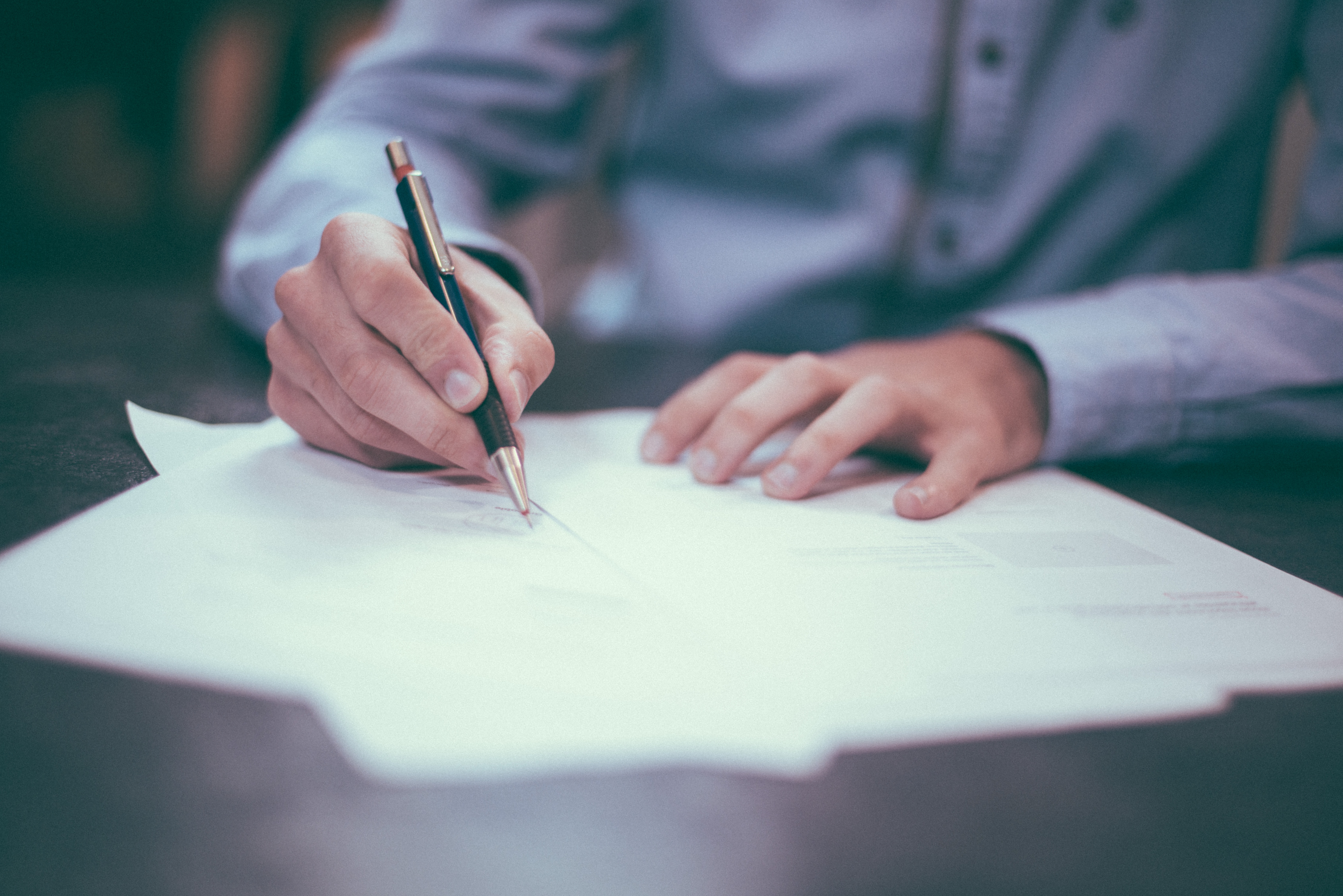 Someone in a shirt signing documents