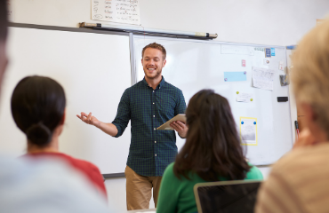 Male teacher teaching a class of young students