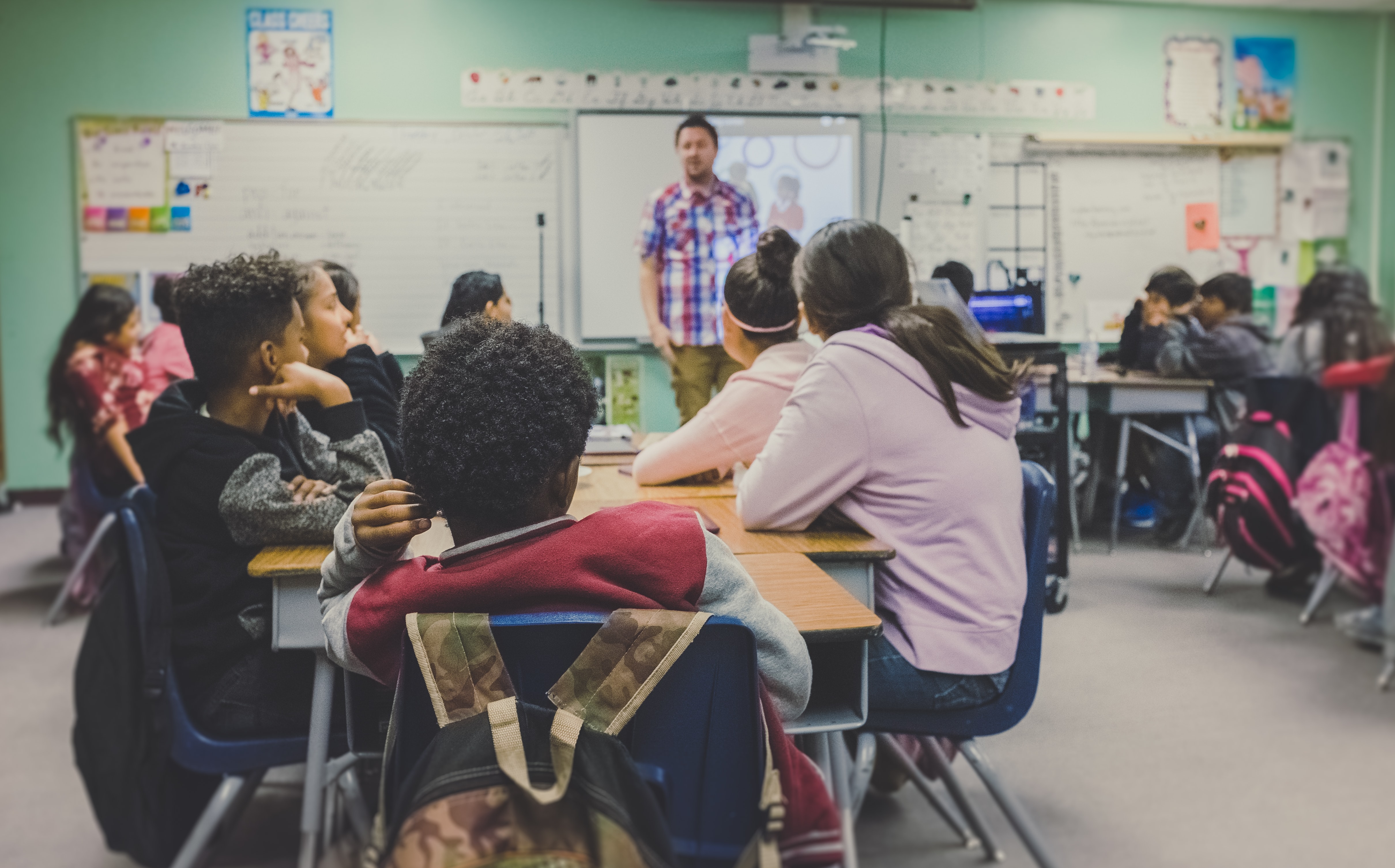 Male teacher teaching a class of young students