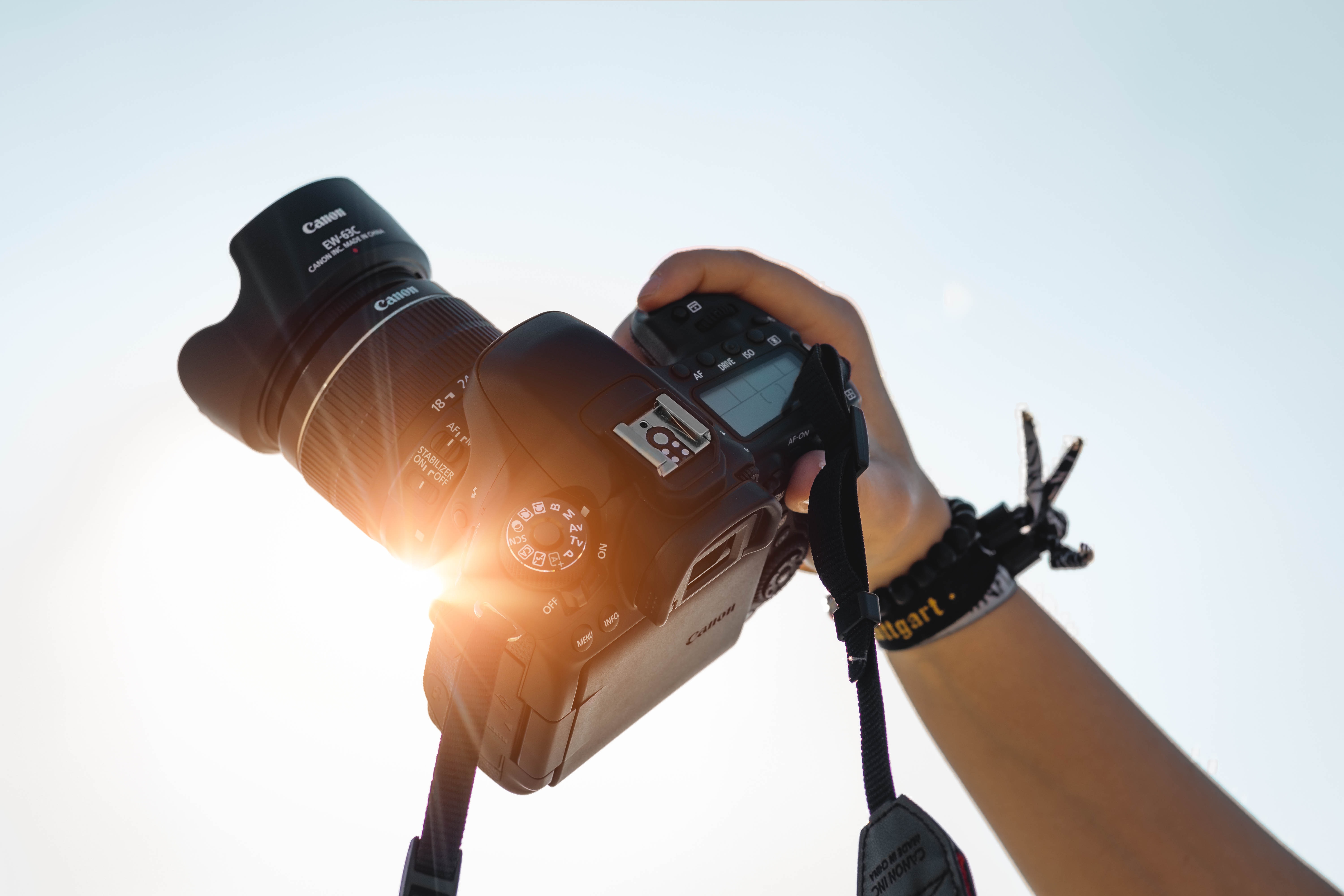 someone holding a camera in front of the sun