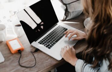 Lady working on a laptop with a hard drive plugged in