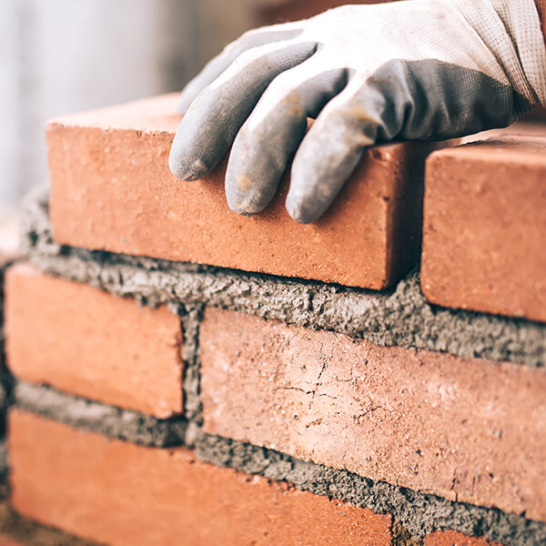 Someone brick laying with gloves on