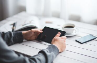 someone leaning on a table with a tablet in hand