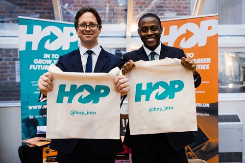 Two men holding up hop branded bags