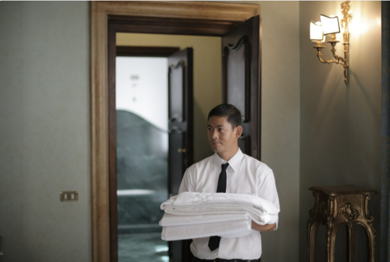 Man in a shirt and tie carrying towels