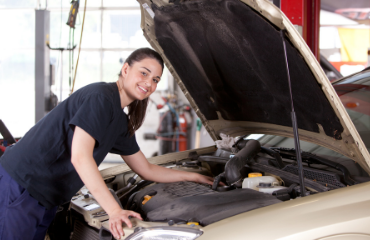 Female machinic looking in the bonnet of a car