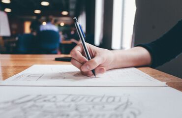 Someone drawing on a piece of paper in a work cafe